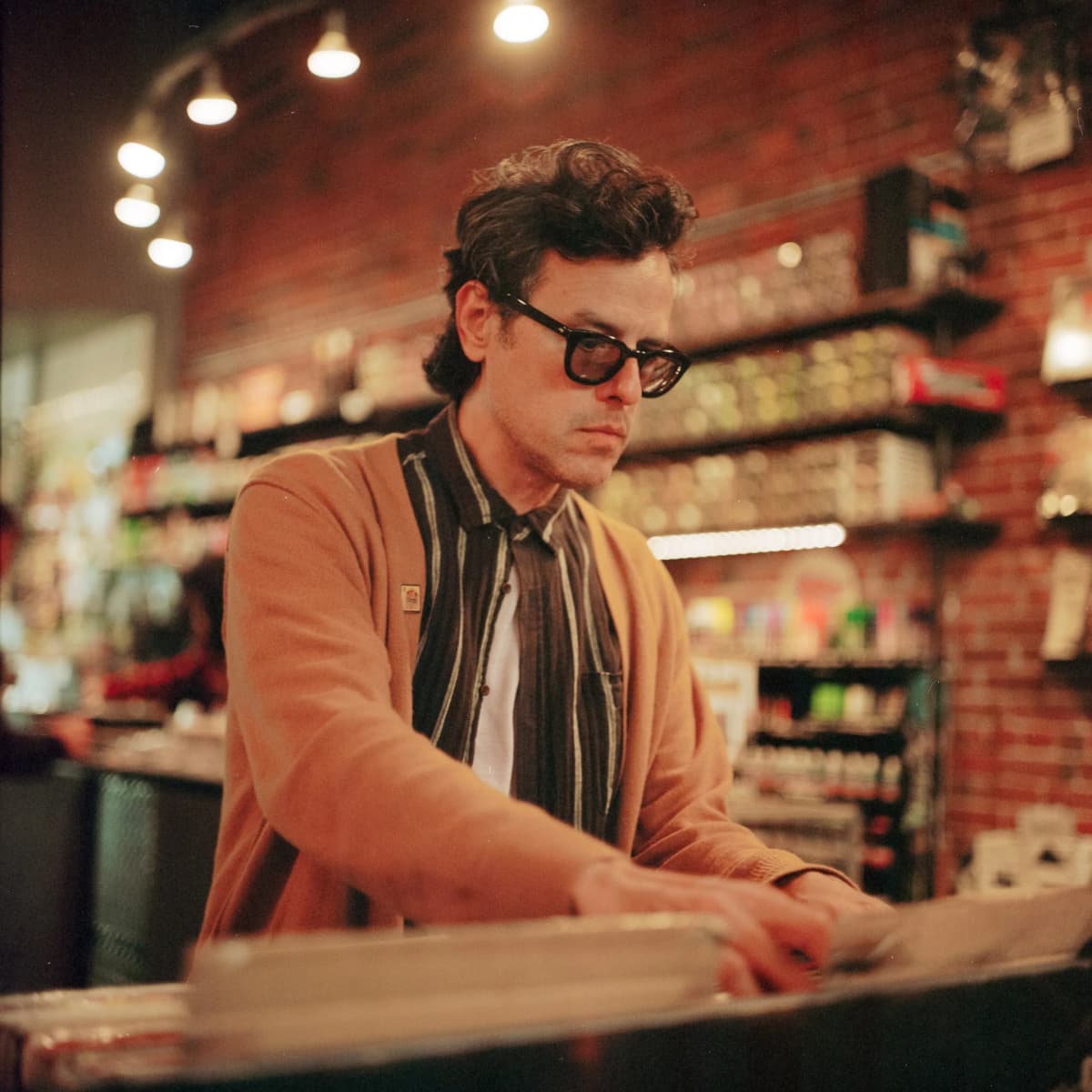 Clemente Castillo browsing through vinyl records at a record store, carefully selecting from rows of albums